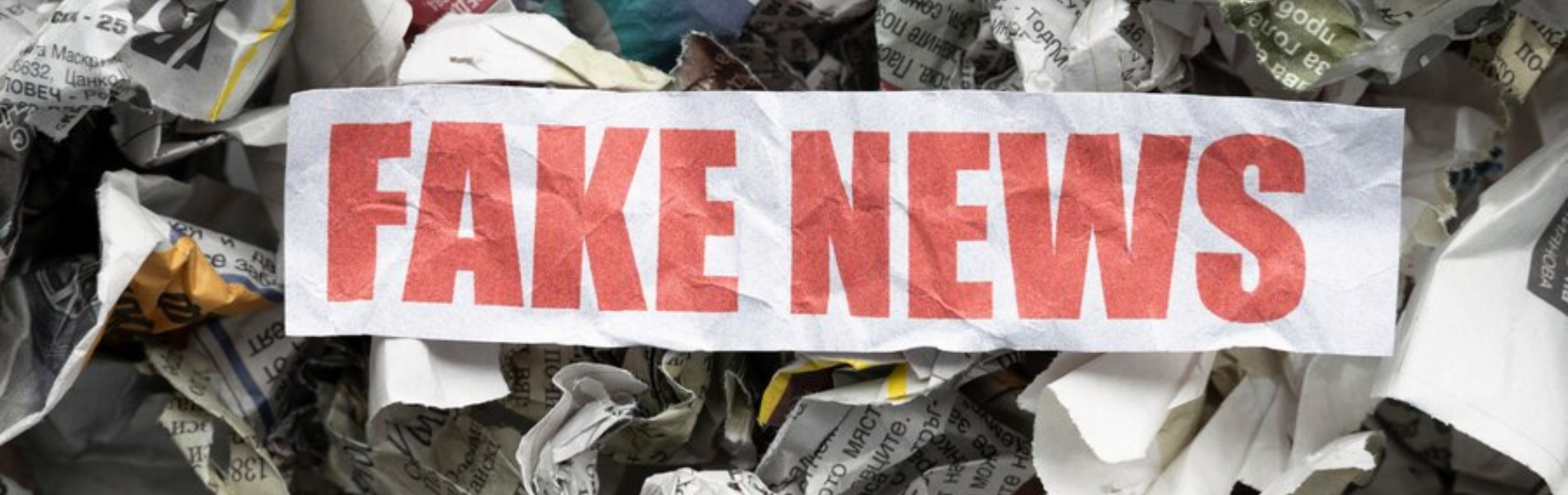 Faixa escrito "Fake News" sobre uma monte de papeis amassados