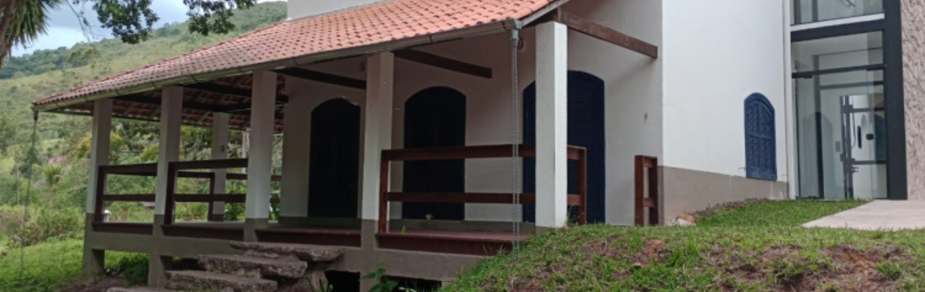 Foto de casa do Quilombo São José, mostrando fachada branca, pequena escada de pedra e grama verde em volta