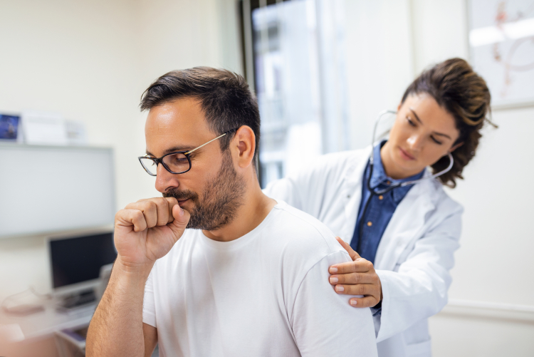 Homem com tosse sendo examinado por médica.