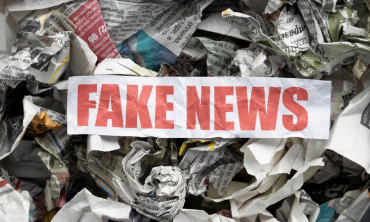 #ParaTodosVerem A imagem mostra um fundo com folhas de jornal amassadas e um pedaço de papel branco em que se lê, em vermelho, “fake news”